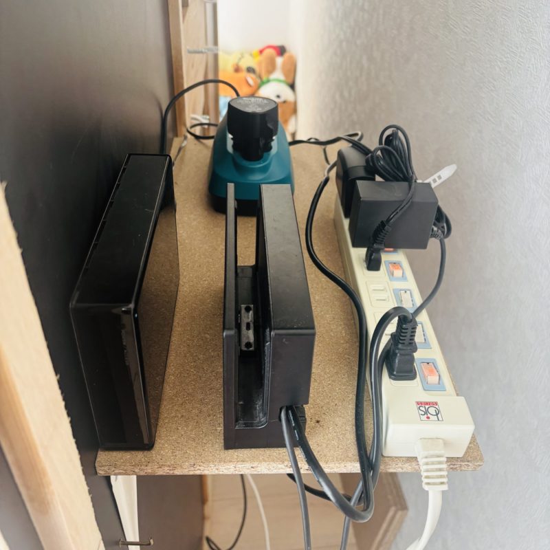 ふかし壁の裏側に棚を設置し電源タップやHDDなどを収納している写真